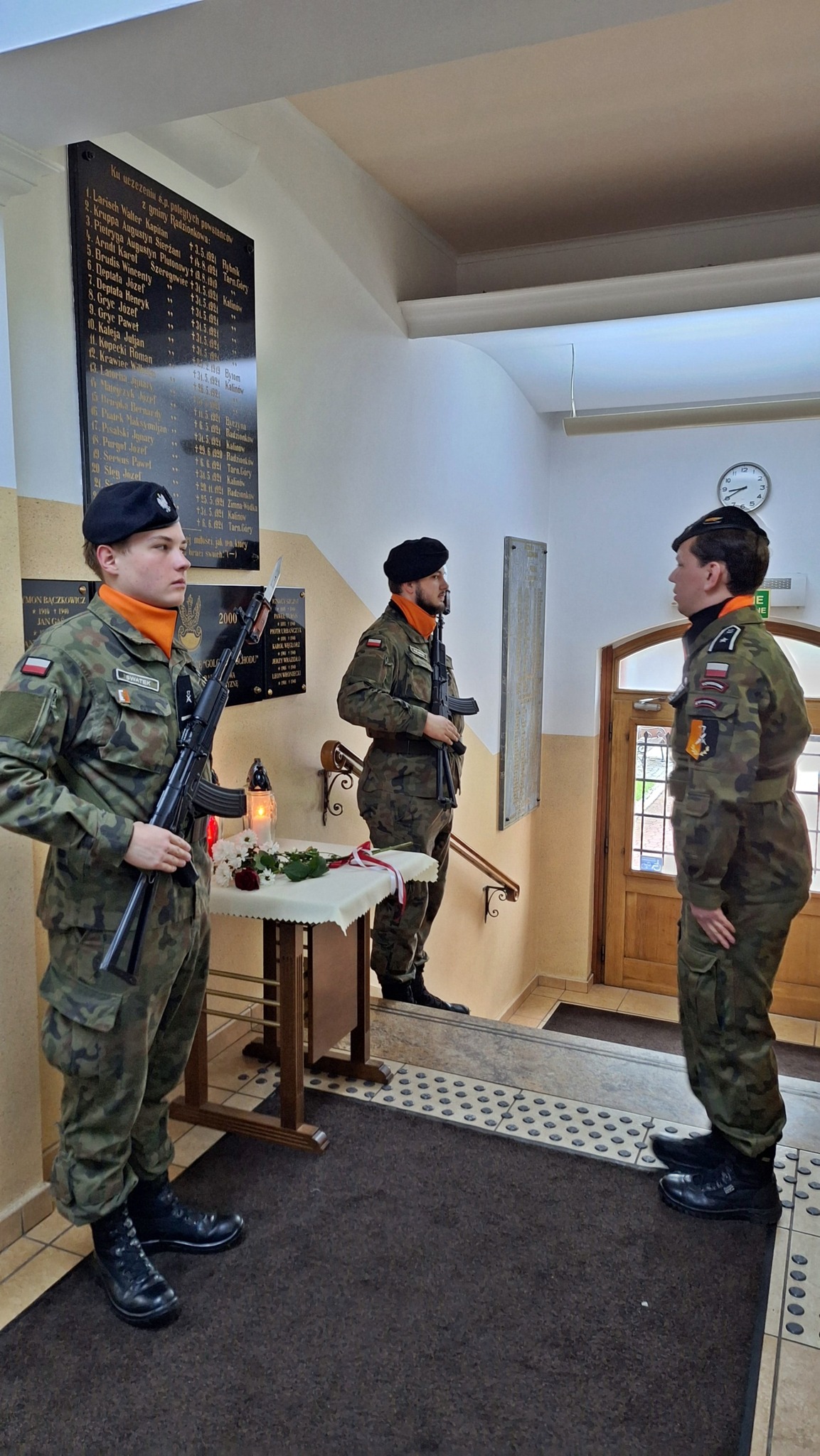 Żołnierz składa hołd przed tablicami upamiętniającymi ofiary zbrodni katyńskiej.