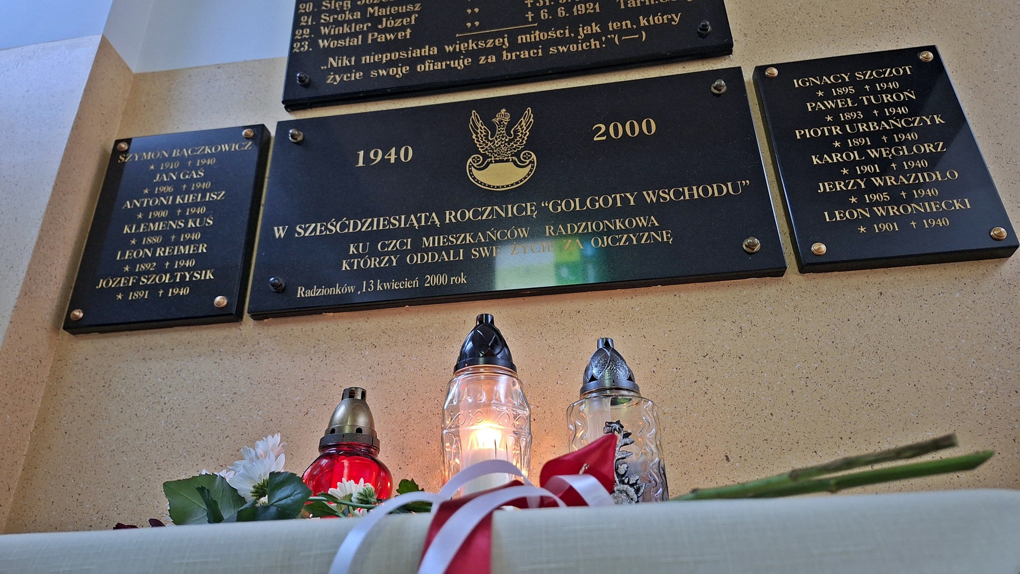 Zapalone znicze przed tablicami upamiętniającymi ofiary zbrodni katyńskiej.