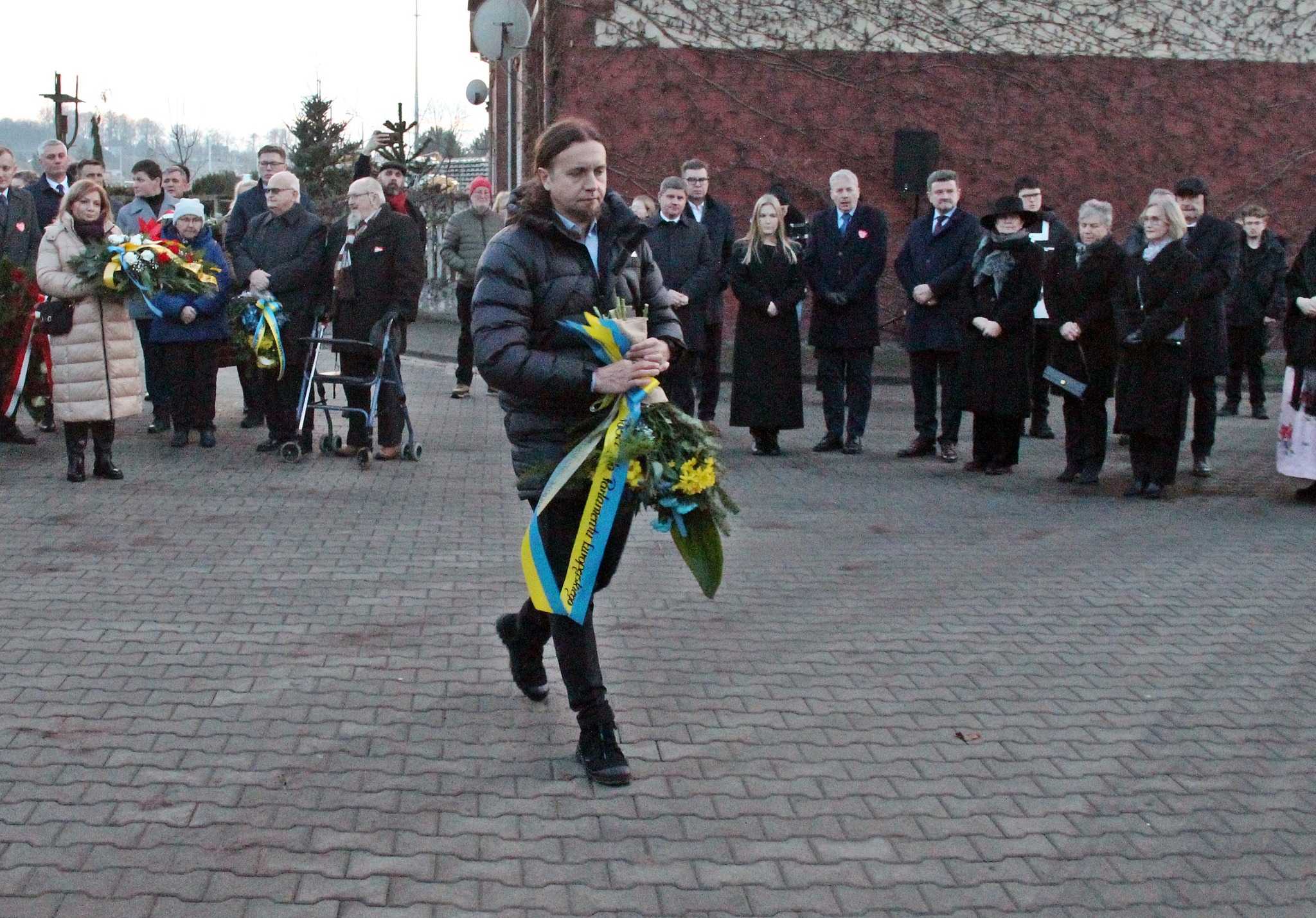 Pan podchodzi z wieńcem do tablicy pamiątkowej