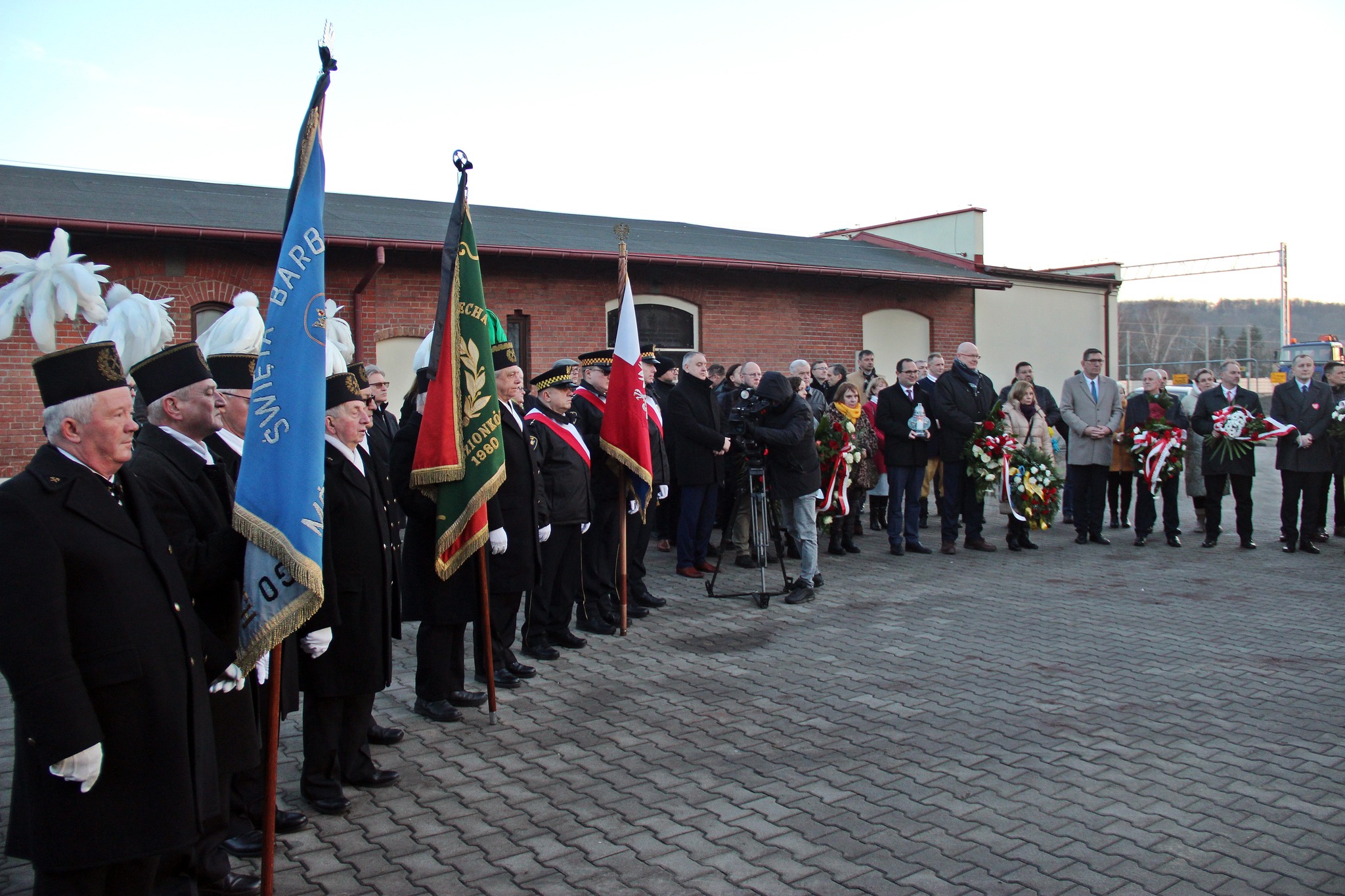 Uczestnicy stojący przed tablicą pamiątkową