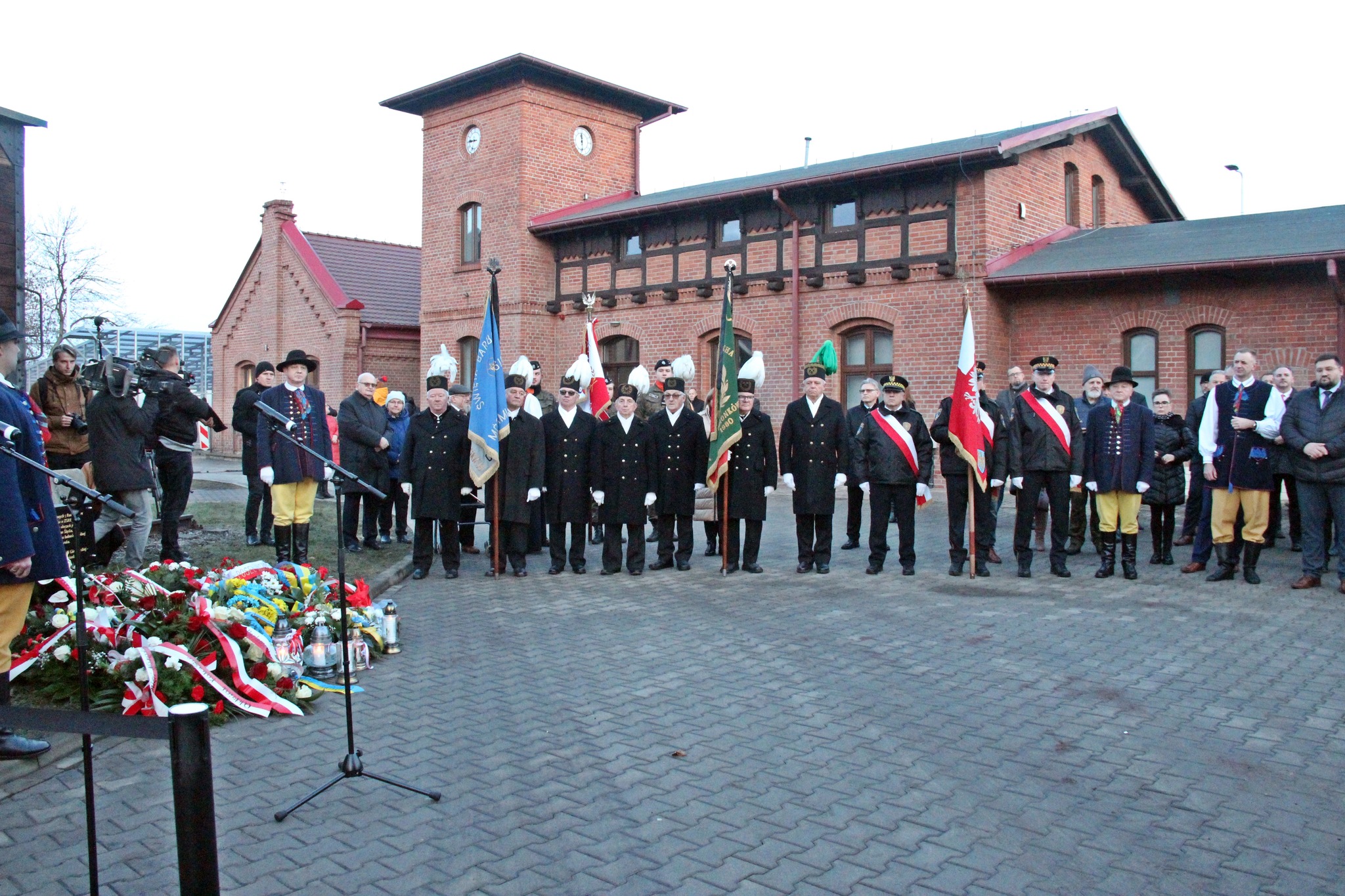 Uczestnicy uroczystości stoją przed tablicą pamiątkową