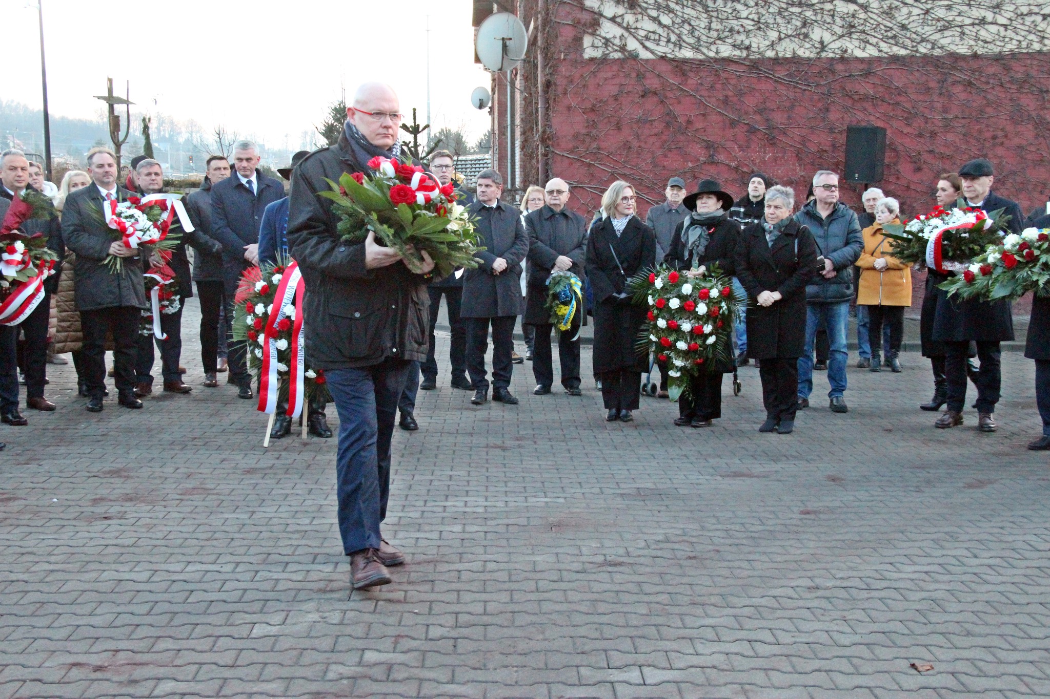 Przedstawiciel urzędu składa wieniec przed tablicą pamiątkową