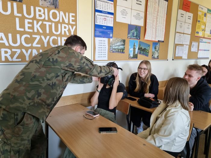 Żołnierz nakłada maskę oddechową uczestniczce szkolenia